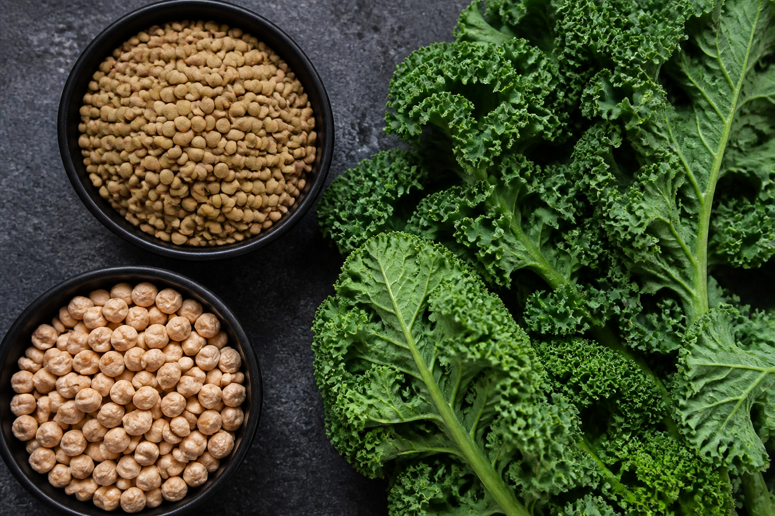 A vibrant flat lay of raw lentils, chickpeas, and fresh kale on a dark stone background, rich textures and high contrast.
